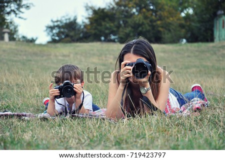 Mom and son make photos with digital camera. Woman photographer taking photo together with her son