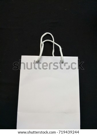 White paper shopping bag on black background.