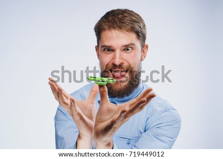 man shows tongue twirls spinner on light background                               