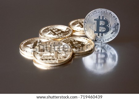 A few gold and silver coins bitcoin lie or stay on edge on a dark background. The concept of crypto currency