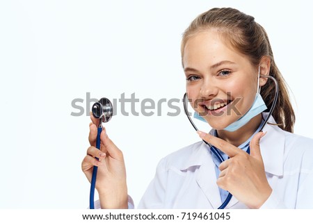 young doctor in medical mask smiling in hand stethoscope on isolated background portrait                               