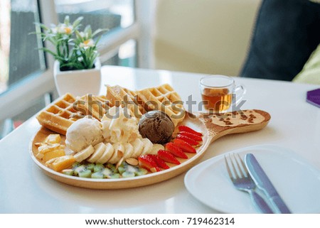 Waffles, ice cream and fruit 
on the table by the window
