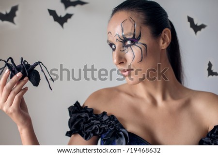Beautiful witch holding spider. Concept Halloween	

