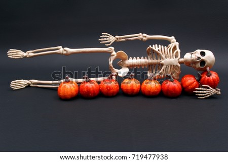 FULL LENGTH SKELETON WITH CLOSED MOUTH ON SIDE NEXT TO ROW OF PUMPKINS