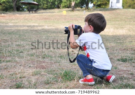Four years old boy taking photos with camera. Little photographer with professional dslr camera