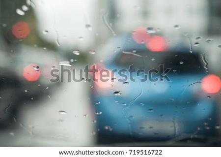 closeup of rain drops on windshield with blurred cars on background
