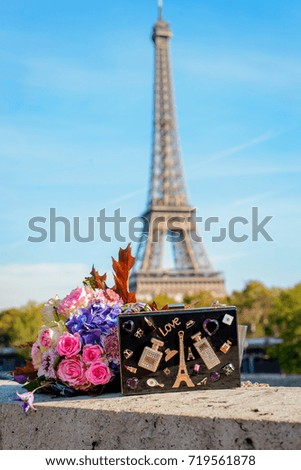 Fashion bag and autumn flowers. Eiffel tower on background