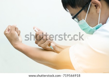 The young man tries to inject medicine into his body,Close up hand holding syringe inject to body,Medical instruments