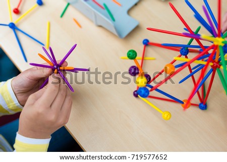 Two little girls playing with lots of colorful plastic sticks kit indoors. kids having fun with building  geometric figures and learning mathematics in preschool or primary class of school