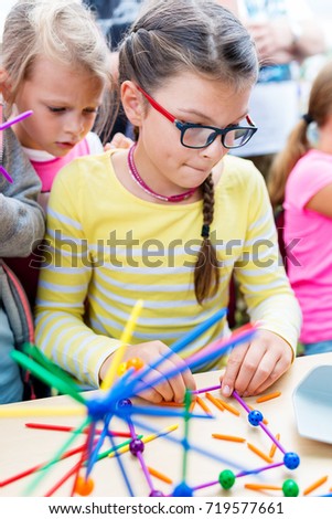 Two little girls playing with lots of colorful plastic sticks kit indoors. kids having fun with building  geometric figures and learning mathematics in preschool or primary class of school