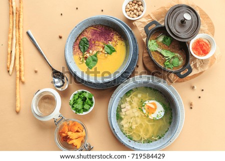 Top view of four partially displayed ceramic and bread bowls full of freshly cooked soup and delicious garnish placed on wooden table