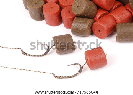 Fishing bait with hook and brown with red pre-drilled halibut pellets for carp fishing isolated on white background with soft shadow