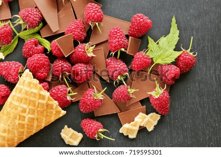 Raspberries with leaves in waffle cone  on dark background 