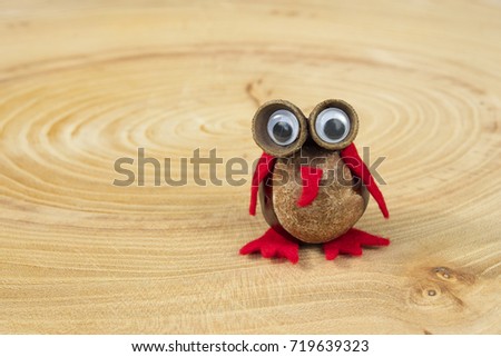 Funny owl shape character or figurine made with chestnuts on a wooden background in a sunny day