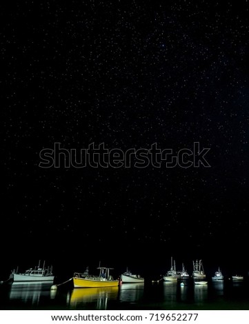 Illuminated boats moored in harbor under starry sky