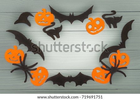 Halloween holiday background made of frame with pumpkins, bats, cats, spiders and hat cut paper on gray board. Copy space. Light up