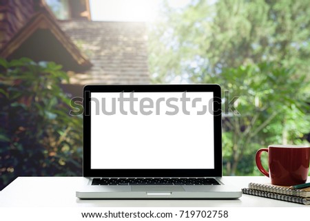 Conceptual Design,Empty workspace on desk white with Laptop screen and notepad and coffee cup at blurred background of house.