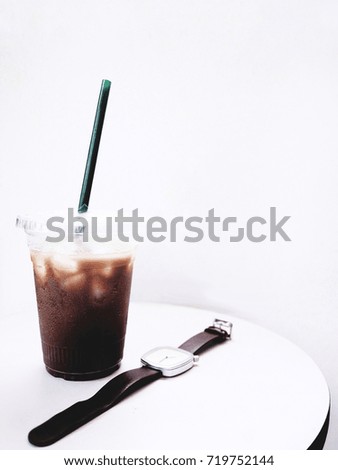The picture of iced mocha and watch on white table on white background. minimal style. selective focus