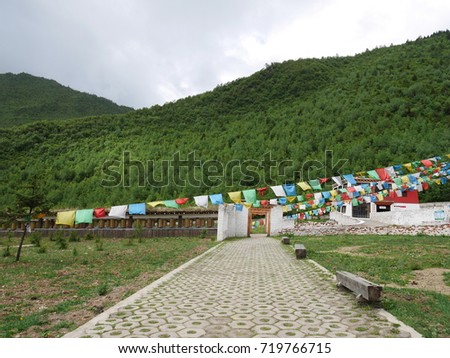 pathway with the mountains as a background, surrounded with Tibet small colorful flags hanging across the picture