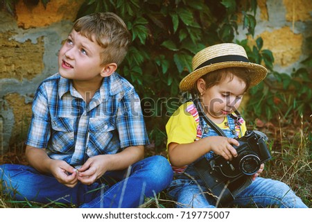 brother and sister with an old camera on the walk .Young cheerful photographer