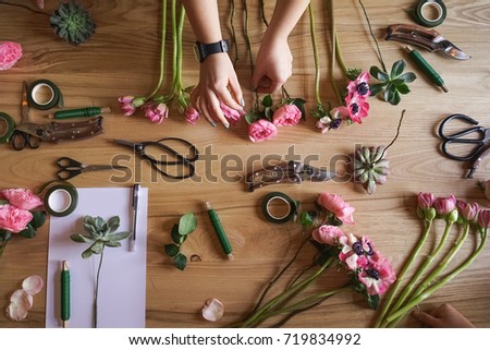 workshop florist. The hand of the girl on the background of the table with flowers. Create floral arrangements. Royalty-Free Stock Photo #719834992