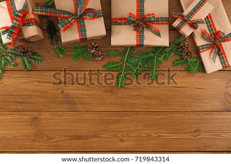 Gift boxes and fir tree twigs border, top view with copy space on wood table background. Frame of colored packages with red, green ribbons for christmas, valentine day or birthday