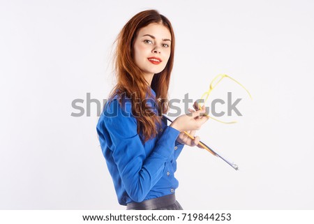 young teacher with her hair in blue shirt looking at the camera on a light background, working in the school                               