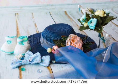 accessories for future mom awaiting for baby boy blue hat knitted booties bouquet with toy stork and flowers in blue tones on wooden floor toned picture close-up shallow depth of field