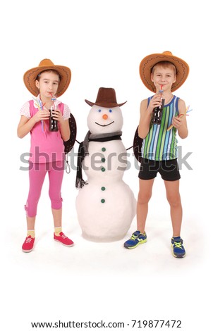 Cute boy and girl holding a cola bottle near a snowman with scarf and hat on white background