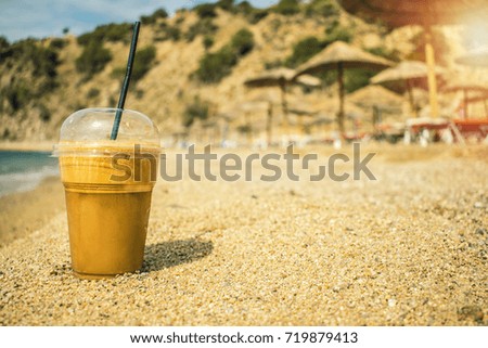 Travel Concept Tourism Concept Tourist Composition with coffee frappe  ice coffee sun glasses and hat on the beach sand blue waters sea ocean 