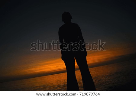 Young man silhouette expressing different feelings of joy, success, dreaming, business opportunity with sunset and sea ocean in the background  