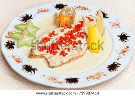 Fillet of a salmon in sauce with red caviar.