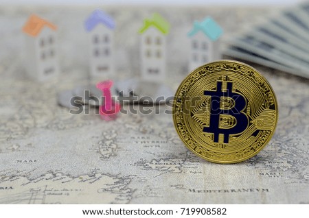 Golden Bitcoins on house model,banknotes,silver coin background.Photo of golden bitcoin (new virtual currency)
