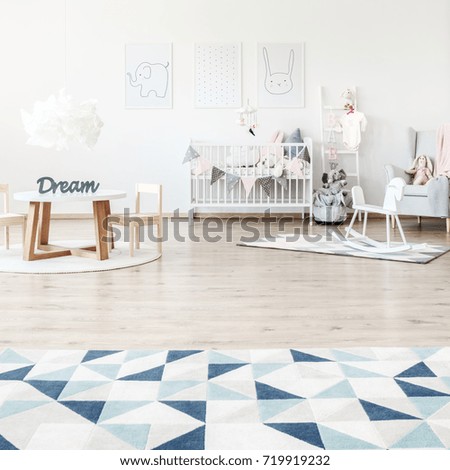 Triangle carpet in spacious kid's room with rocking horse, small table and white bed