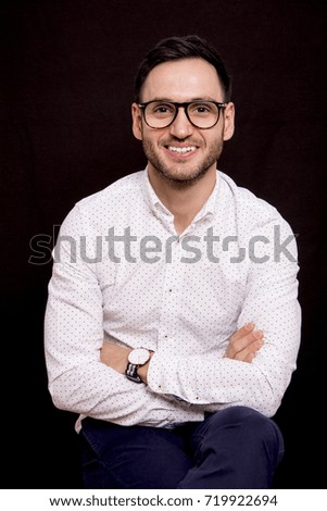 Portrait of a handsome guy on black background. Stylish pose with glasses. 