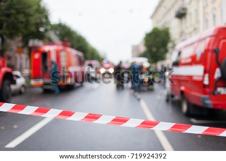 Red and White Lines of barrier tape on the background of firefighters and fire trucks at work.. Red White warning tape pole fencing is protects for No entry.