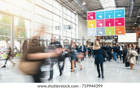 Anonymous blurred business people rushing in a hall of a trade f