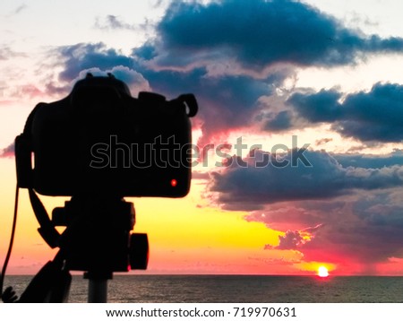Dslr camera photographing Tuscany hills. Dslr camera shooting on a cityscape sunset with sea reflection