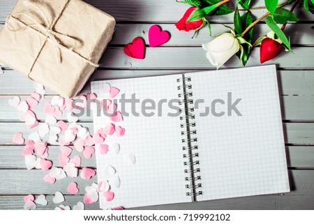 rose flowers and hearts with gift box and blank note book on wooden background. Top view with copy space. Holiday mockup.