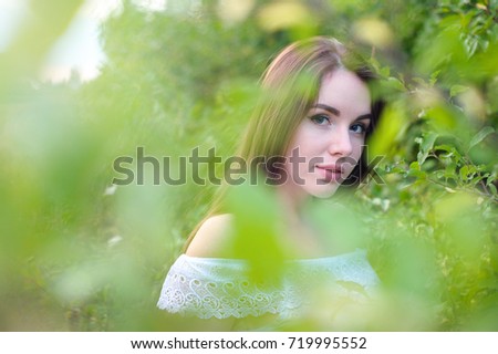 portrait of a young beautiful girl in a park in white dress