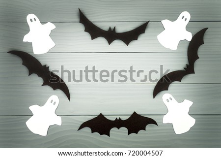 Halloween holiday background made of frame with bats and ghosts cut paper on gray board. Copy space. Light up