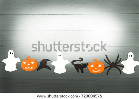 Halloween holiday background with pumpkins, cat, spider, hat and ghosts cut paper on gray board. Copy space. Light up