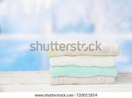 A stack of sweaters on the wooden table.