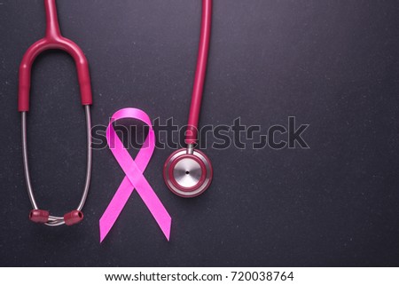 Breast Cancer concept : Pink ribbon symbol of breast cancer and doctor Stethoscope 
on black stone board background