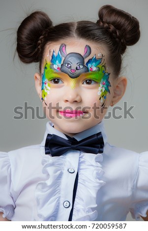 Little girl with a picture of the rabbit on the face on gray background