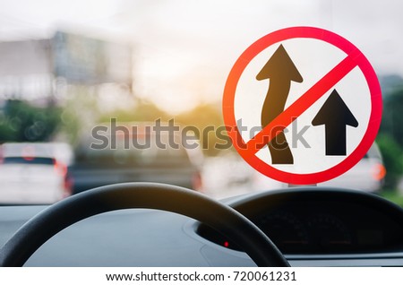 No Overtaking warning sign and inside car view ,steering wheel on blur traffic road with colorful bokeh light abstract background. Copy space of transportation and travel concept. Vintage tone color.