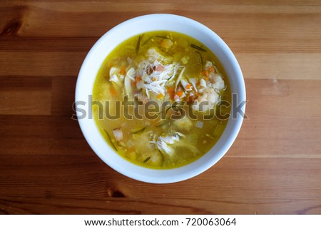 Homemade chicken and dumpling soup on a wooden table. 