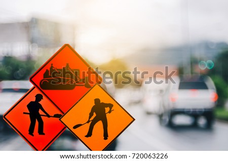 Set of under construction and tractor warning sign on blur traffic road colorful bokeh light abstract background. Copy space of transportation and travel concept. Retro tone filter effect color style.