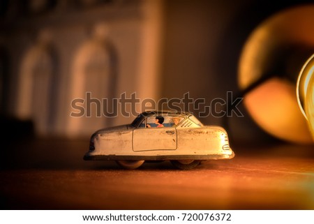A toy car close up going towards the left  with a warm light in the background. The toy is made of metal with 2 characters painted on it. 