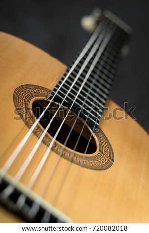 Acoustic guitar detail laying on dark gray background in perspective, selective focus